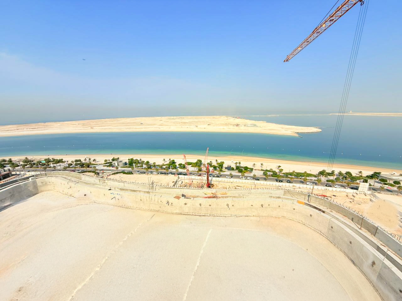 Beach Walk Iii By Imtiaz A panoramic view of a coastal landscape with blue water, sandy shores, and construction in the foreground.